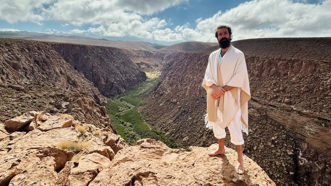 Awe standing in white robes at the rim of a vast canyon