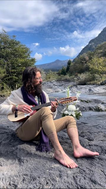 Awe playing music barefoot on river rocks beneath the mountains